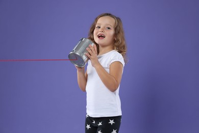 Photo of Girl using tin can telephone on violet background