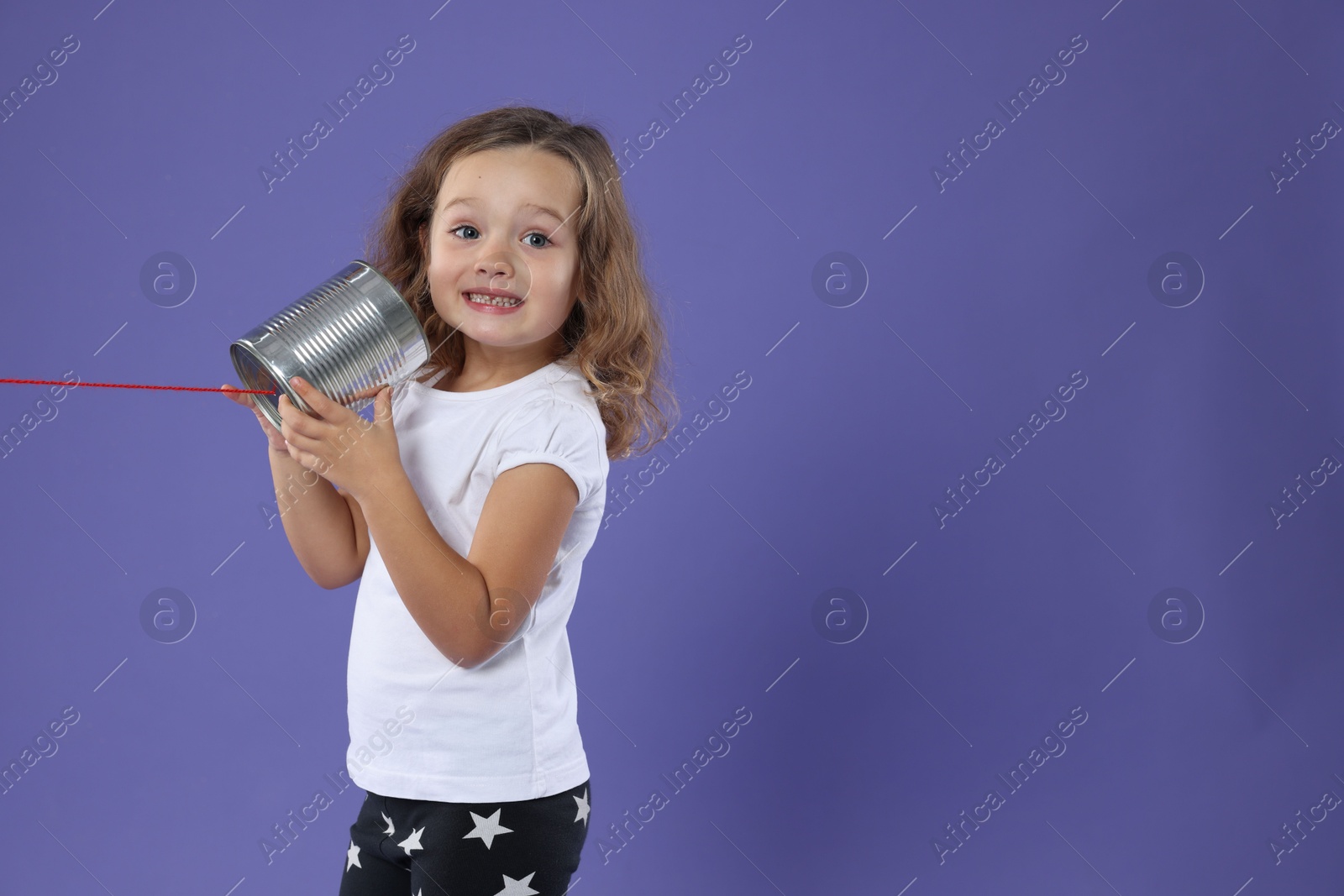 Photo of Girl using tin can telephone on violet background. Space for text