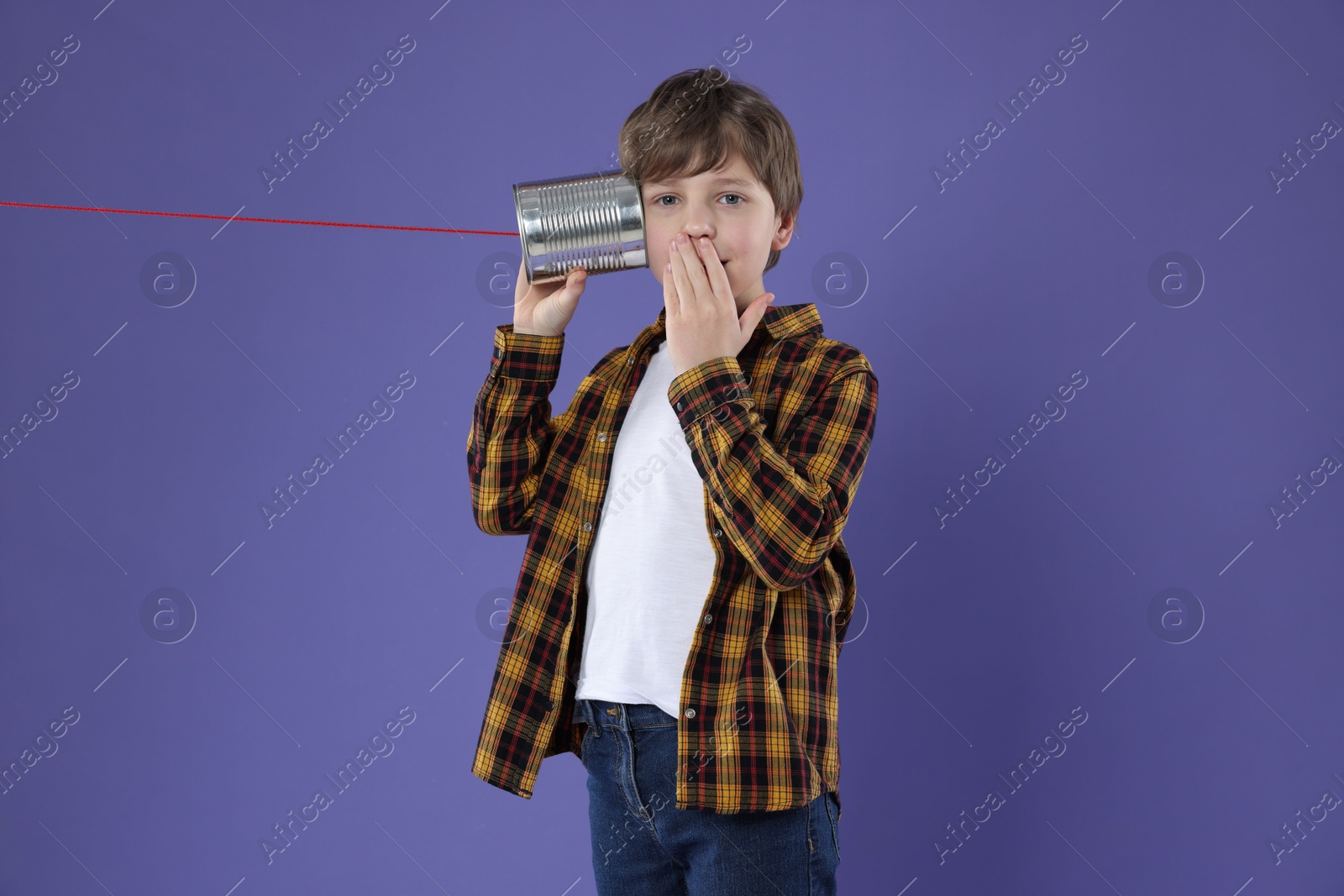 Photo of Boy using tin can telephone on violet background