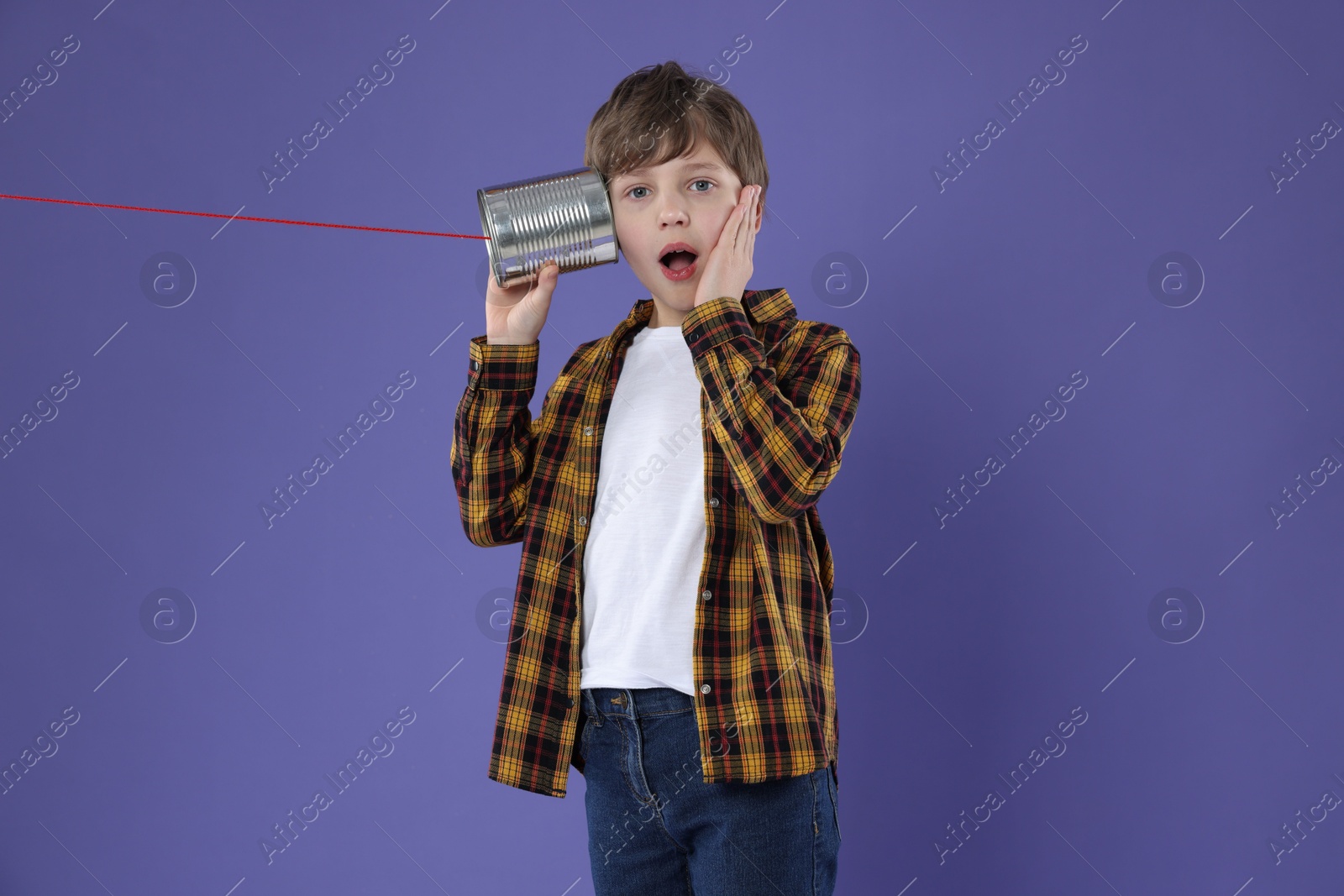 Photo of Boy using tin can telephone on violet background