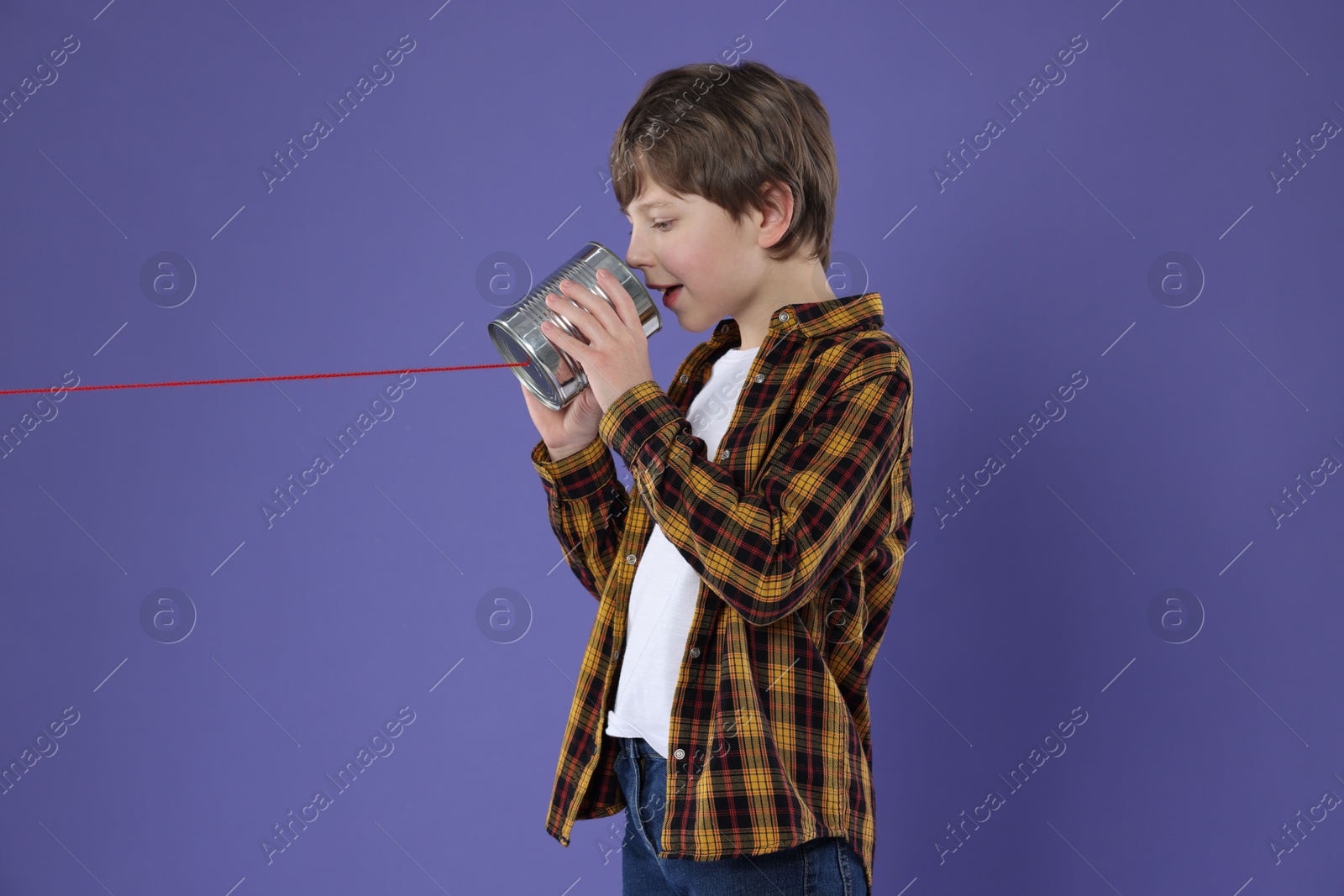 Photo of Boy using tin can telephone on violet background