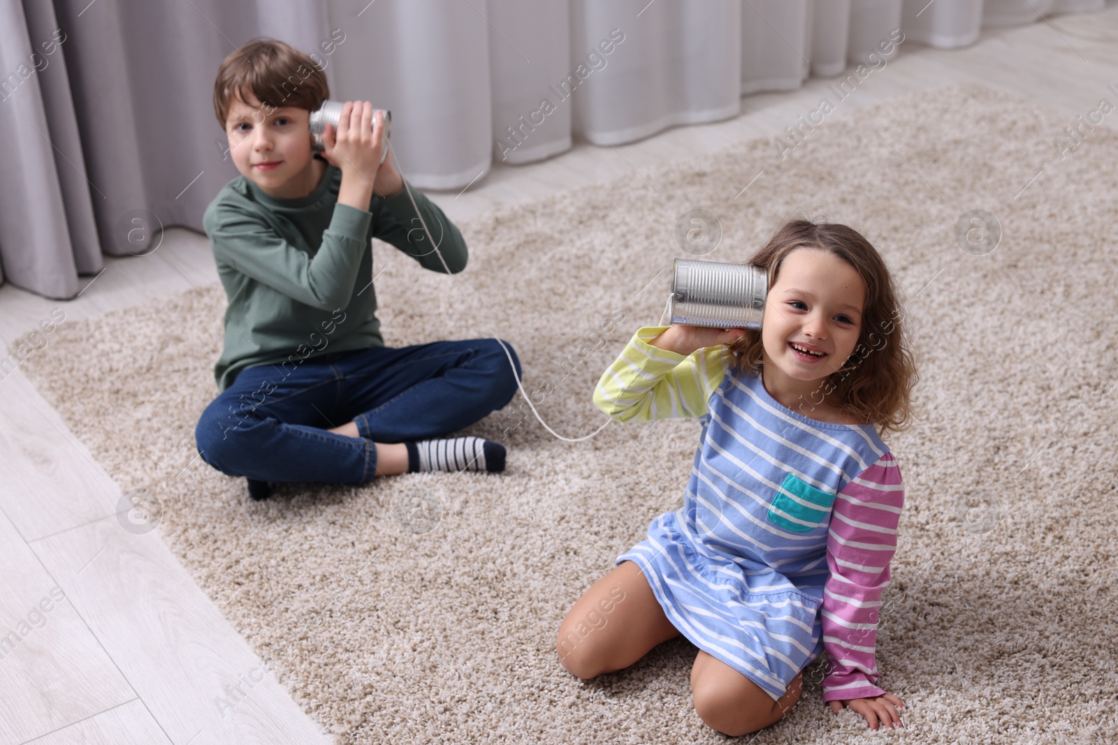 Photo of Boy and girl using tin can telephone indoors