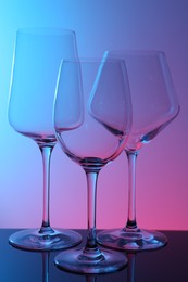 Photo of Empty glasses on table against color background