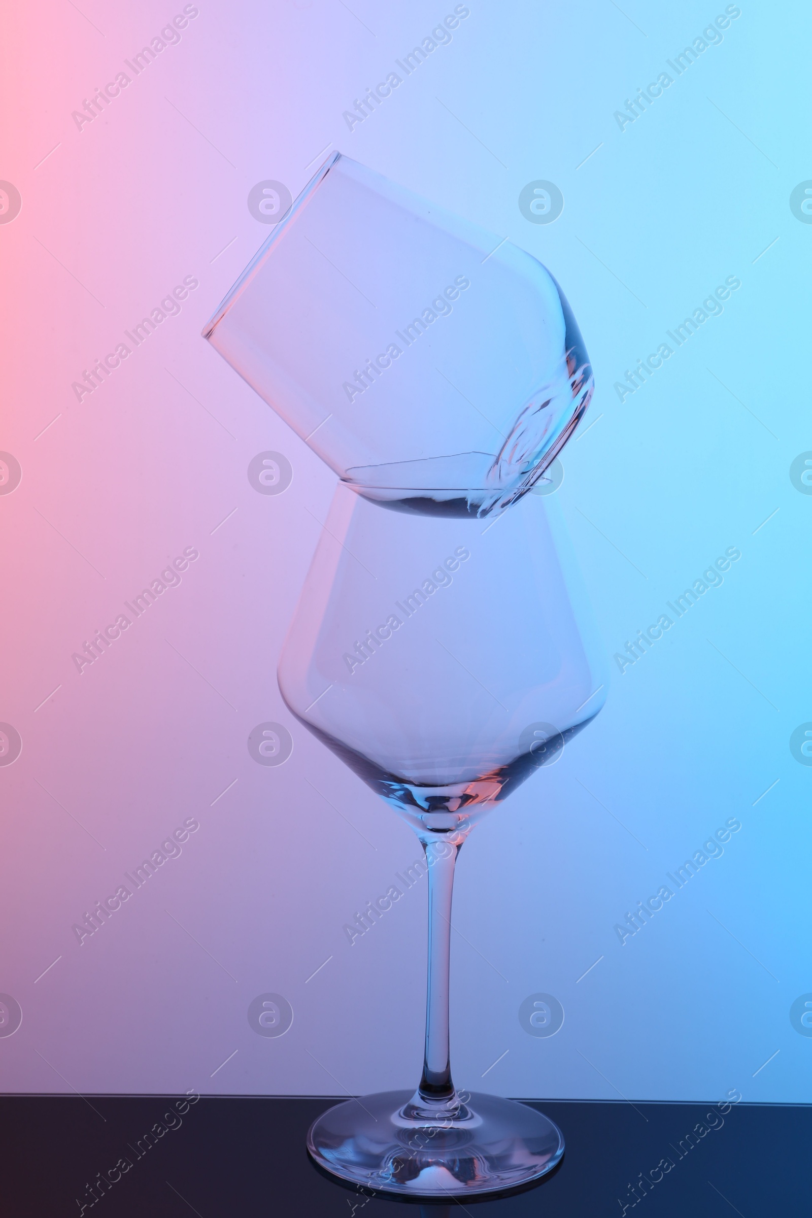 Photo of Empty glasses on table against color background