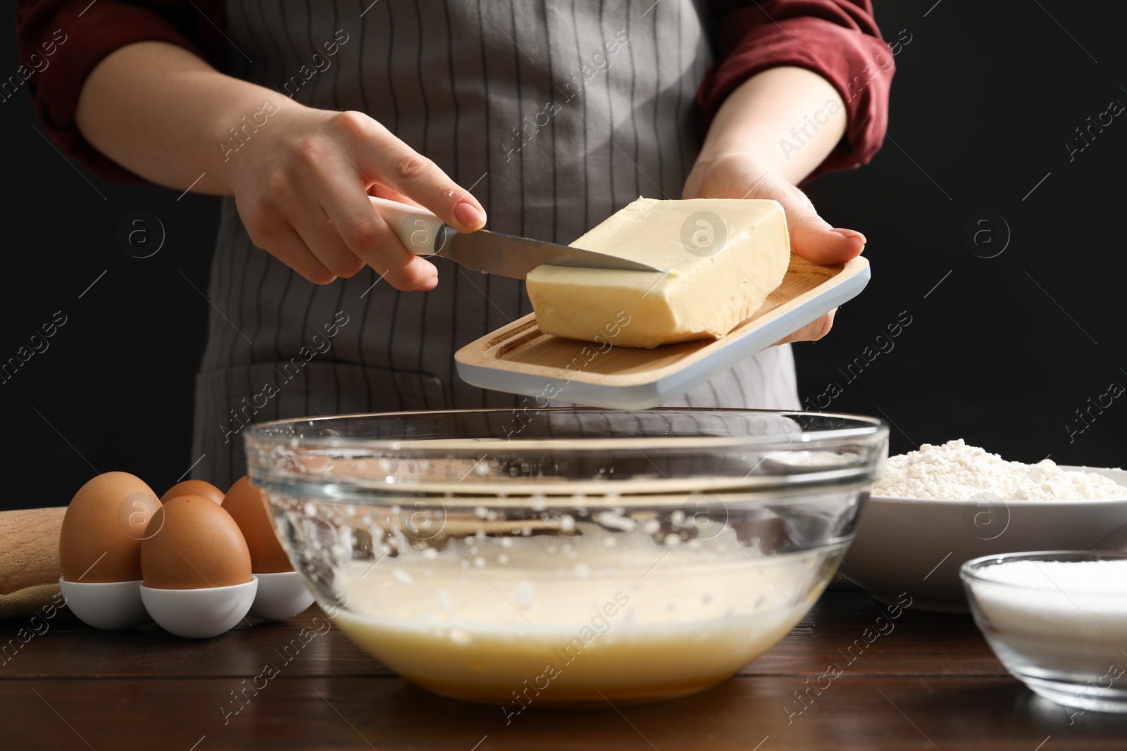 Photo of Making cookies. Woman adding butter into dough at table, closeup