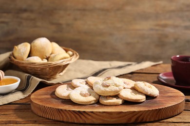 Photo of Tasty cashew cookies with powdered sugar on wooden table, closeup