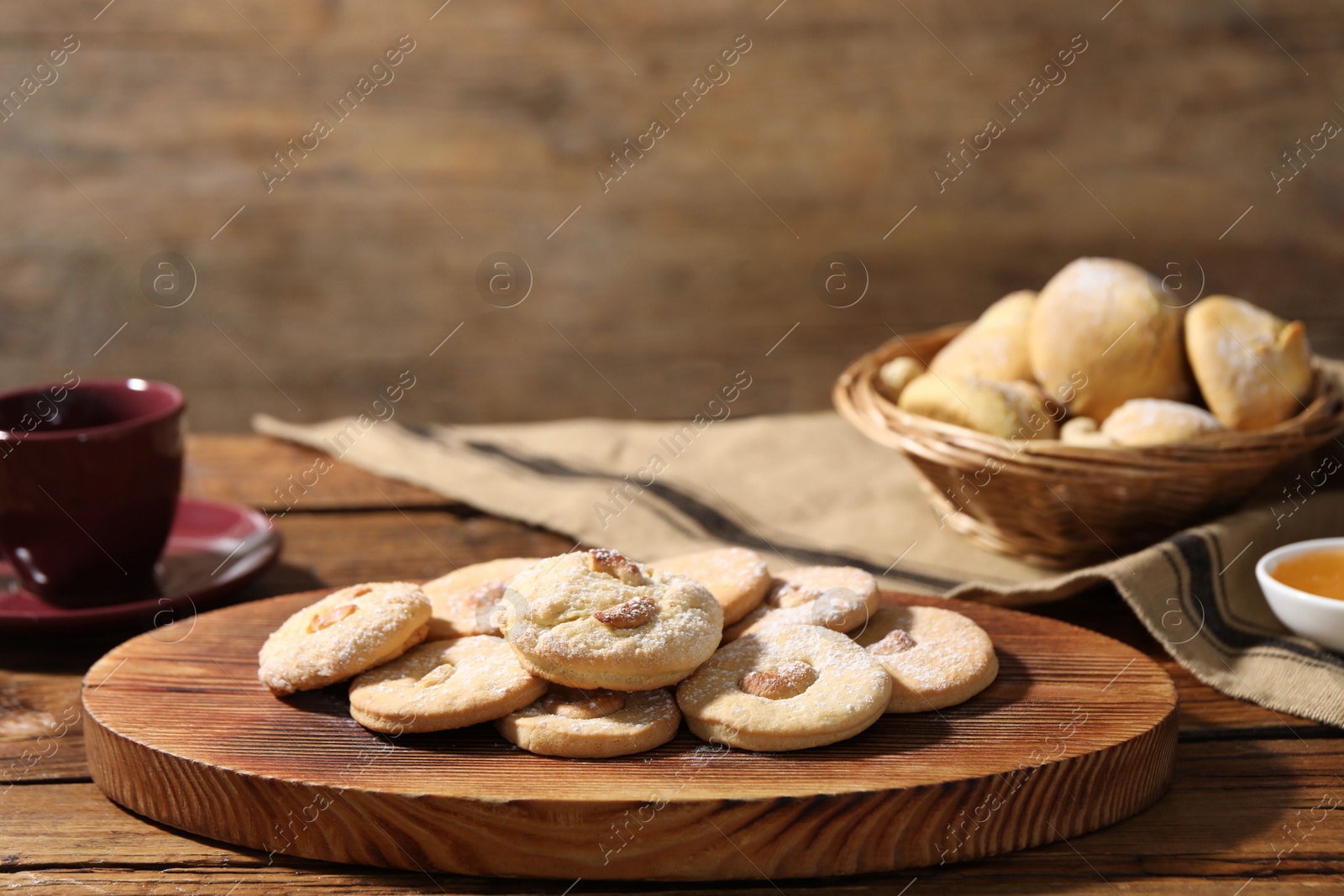 Photo of Tasty cashew cookies with powdered sugar on wooden table, closeup