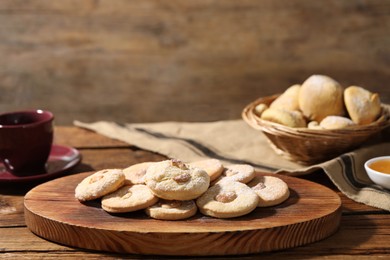 Photo of Tasty cashew cookies with powdered sugar on wooden table, closeup