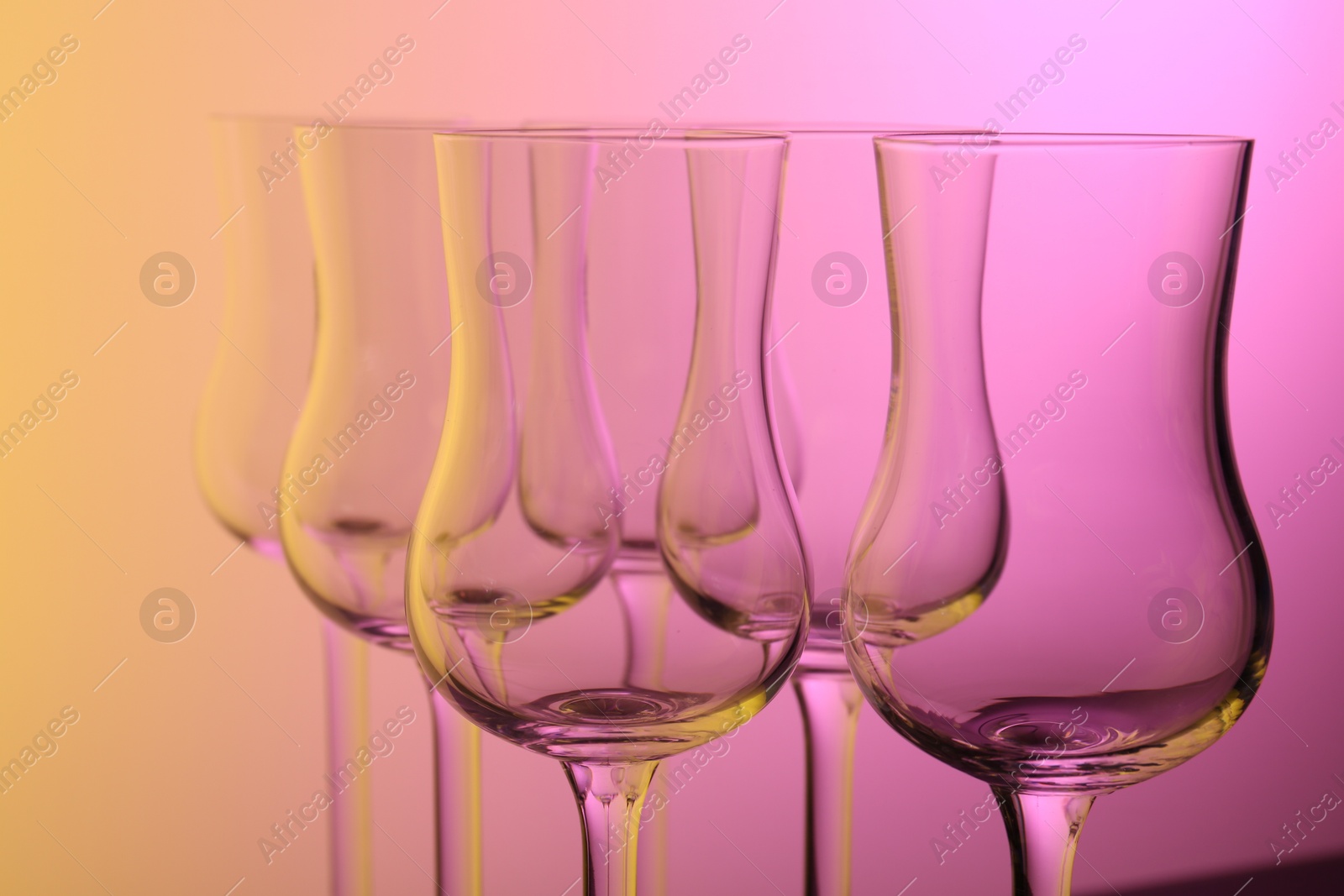 Photo of Empty glasses against color gradient background, closeup