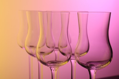 Photo of Empty glasses against color gradient background, closeup