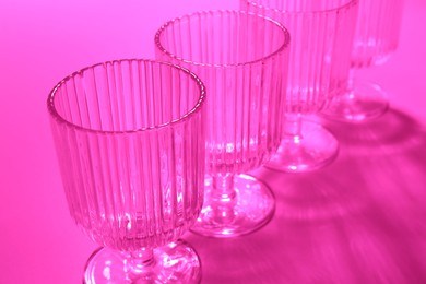 Photo of Empty glasses on pink background, closeup. Color tone effect