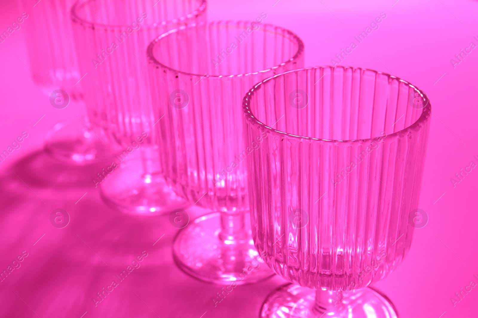 Photo of Empty glasses on pink background, closeup. Color tone effect