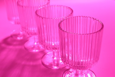 Photo of Empty glasses on pink background, closeup. Color tone effect