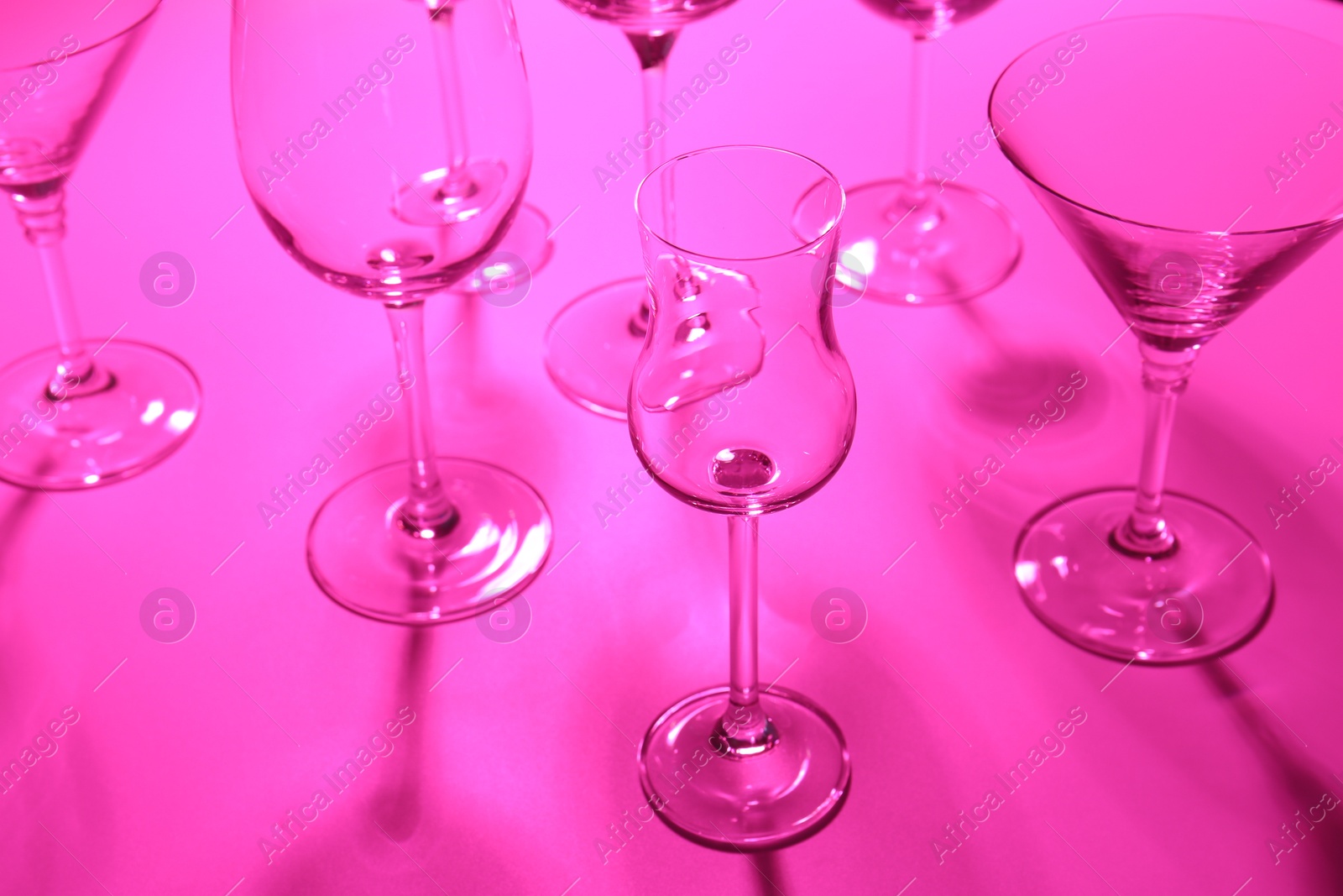 Photo of Empty glasses on pink background, closeup. Color tone effect