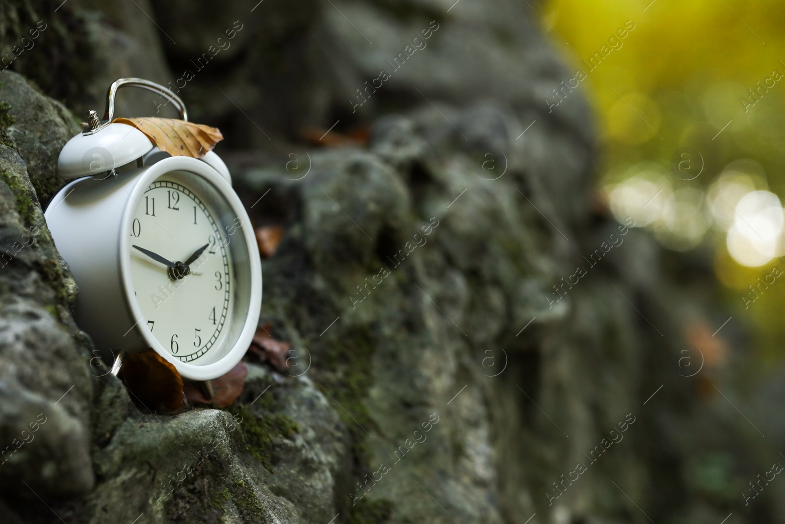 Photo of Alarm clock on stones outdoors, closeup. Space for text