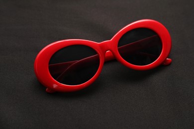 Photo of Stylish sunglasses on black background, closeup. Elegant accessory