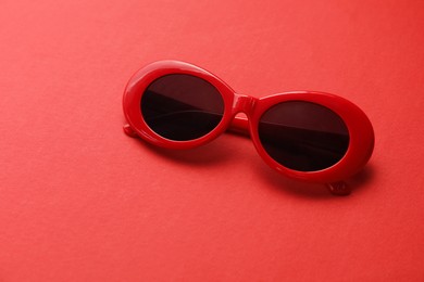 Photo of Stylish sunglasses on red background. Elegant accessory