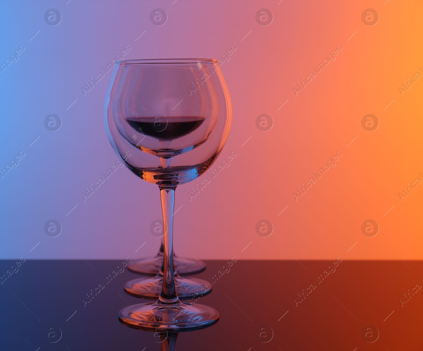 Photo of Wine glasses on table against color background