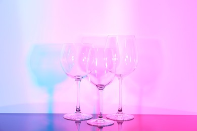 Photo of Empty glasses on table against color background