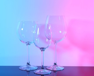 Photo of Empty glasses on table against color background