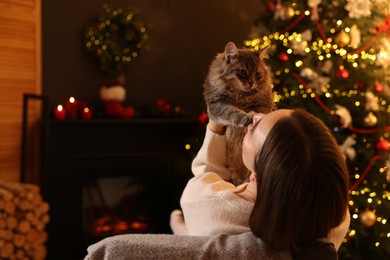 Photo of Woman with cute cat in room decorated for Christmas, space for text