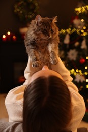 Photo of Woman with cute cat in room decorated for Christmas