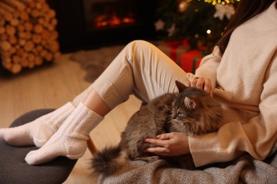 Woman with cute cat in room decorated for Christmas, closeup