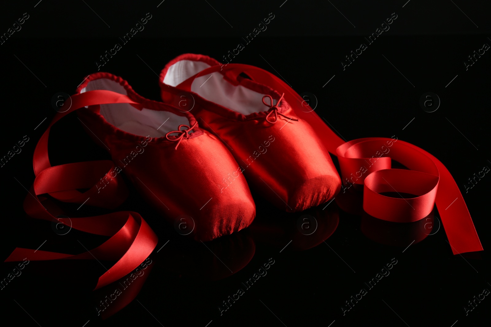 Photo of Pair of beautiful pointe shoes on black mirror surface