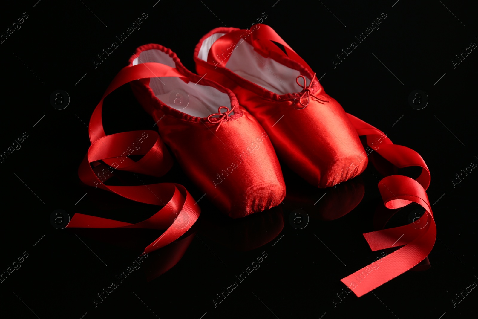 Photo of Pair of beautiful pointe shoes on black mirror surface