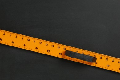 Photo of One ruler on black chalkboard, top view. Space for text