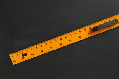 Photo of One ruler on black chalkboard, top view