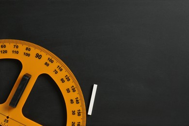 Photo of Protractor ruler and chalk on black chalkboard, top view. Space for text