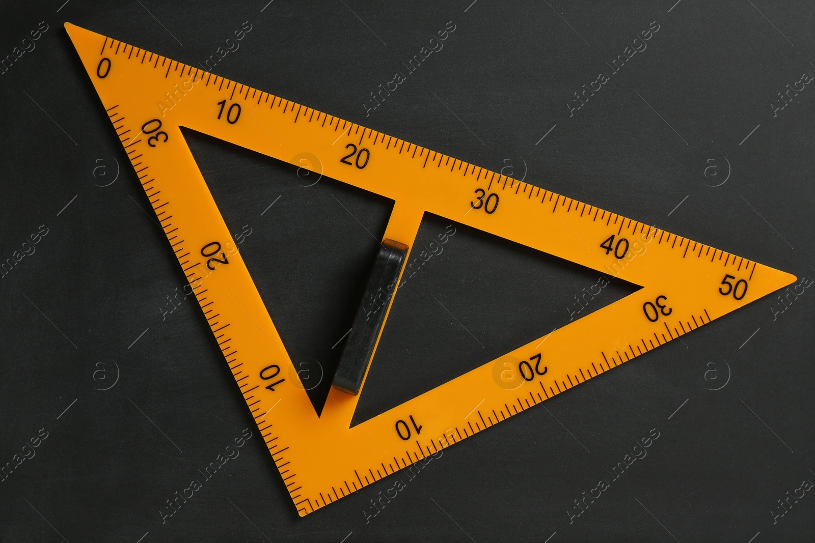 Photo of Triangle ruler on black chalkboard, top view