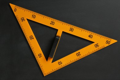 Photo of Triangle ruler on black chalkboard, top view