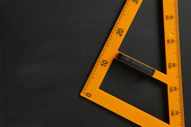 Photo of Triangle ruler on black chalkboard, top view. Space for text