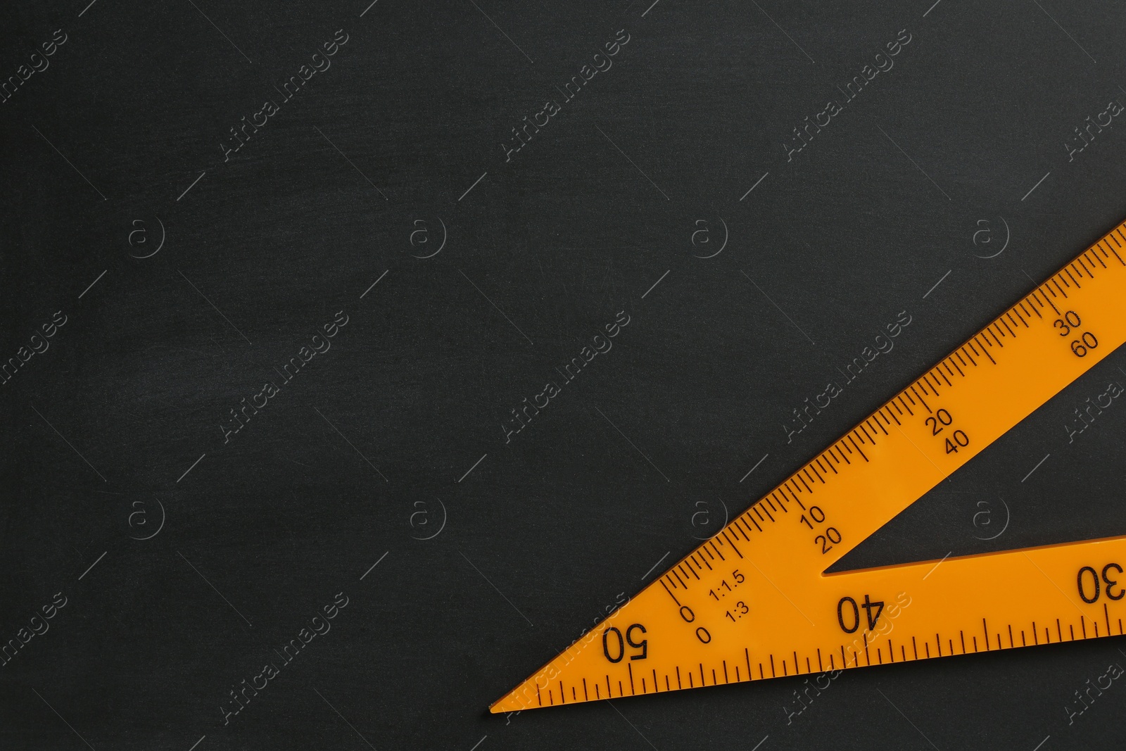 Photo of Triangle ruler on black chalkboard, top view. Space for text