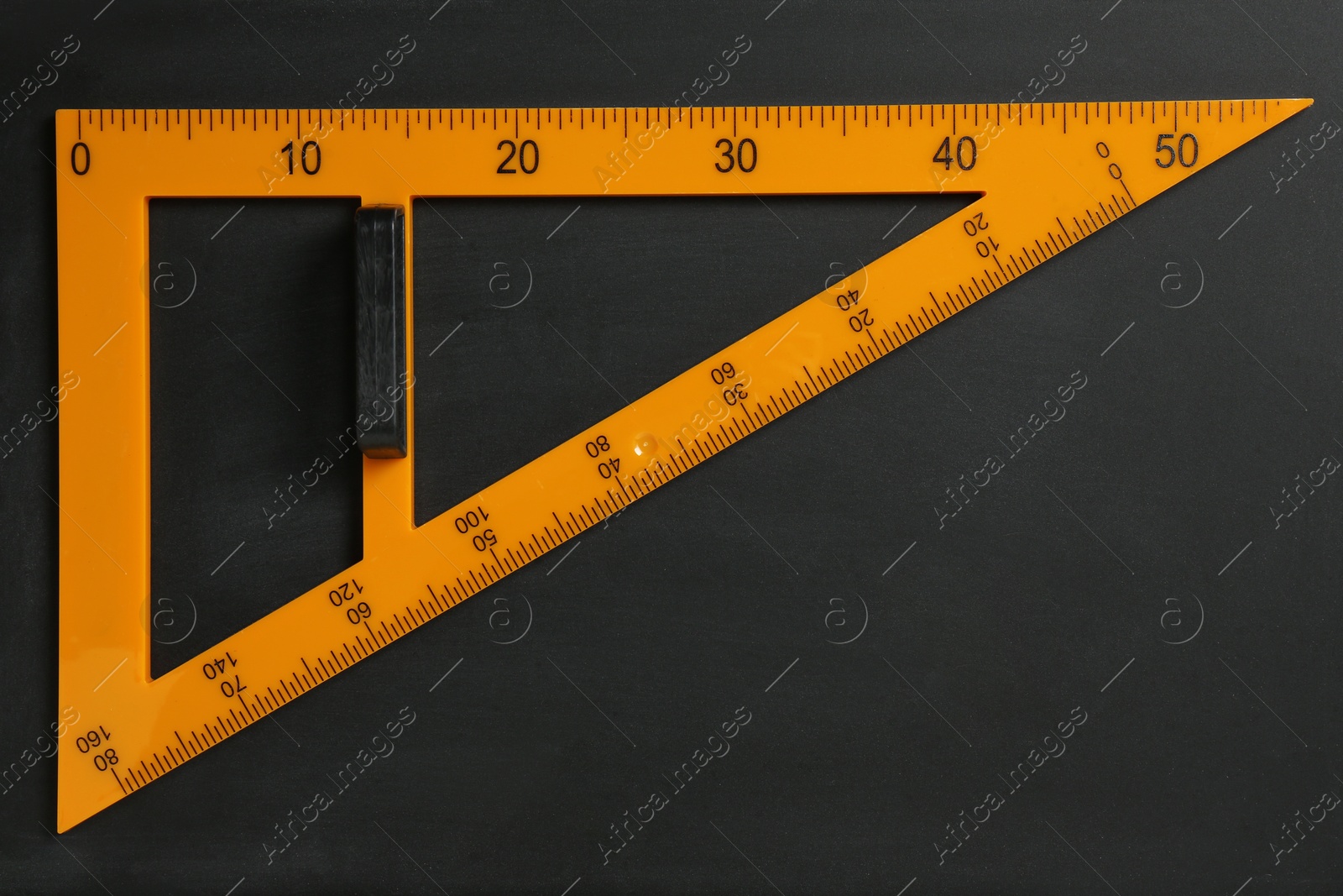 Photo of Triangle ruler on black chalkboard, top view. Space for text