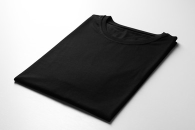 Photo of Blank black t-shirt on white background, closeup. Mockup for design