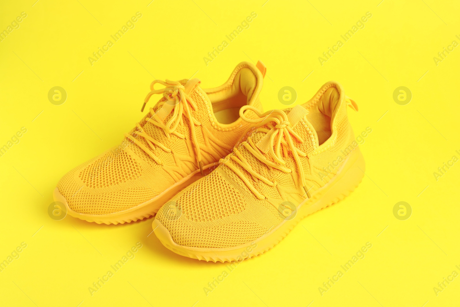 Photo of Pair of stylish sneakers on yellow background