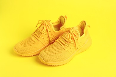 Photo of Pair of stylish sneakers on yellow background