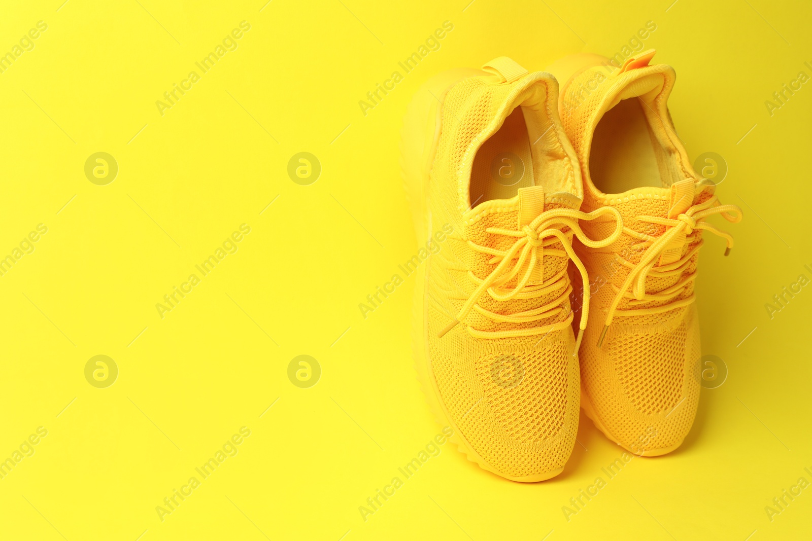 Photo of Pair of stylish sneakers on yellow background. Space for text