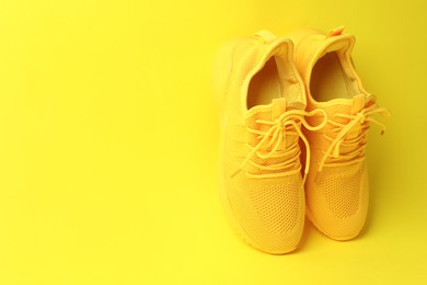 Photo of Pair of stylish sneakers on yellow background. Space for text