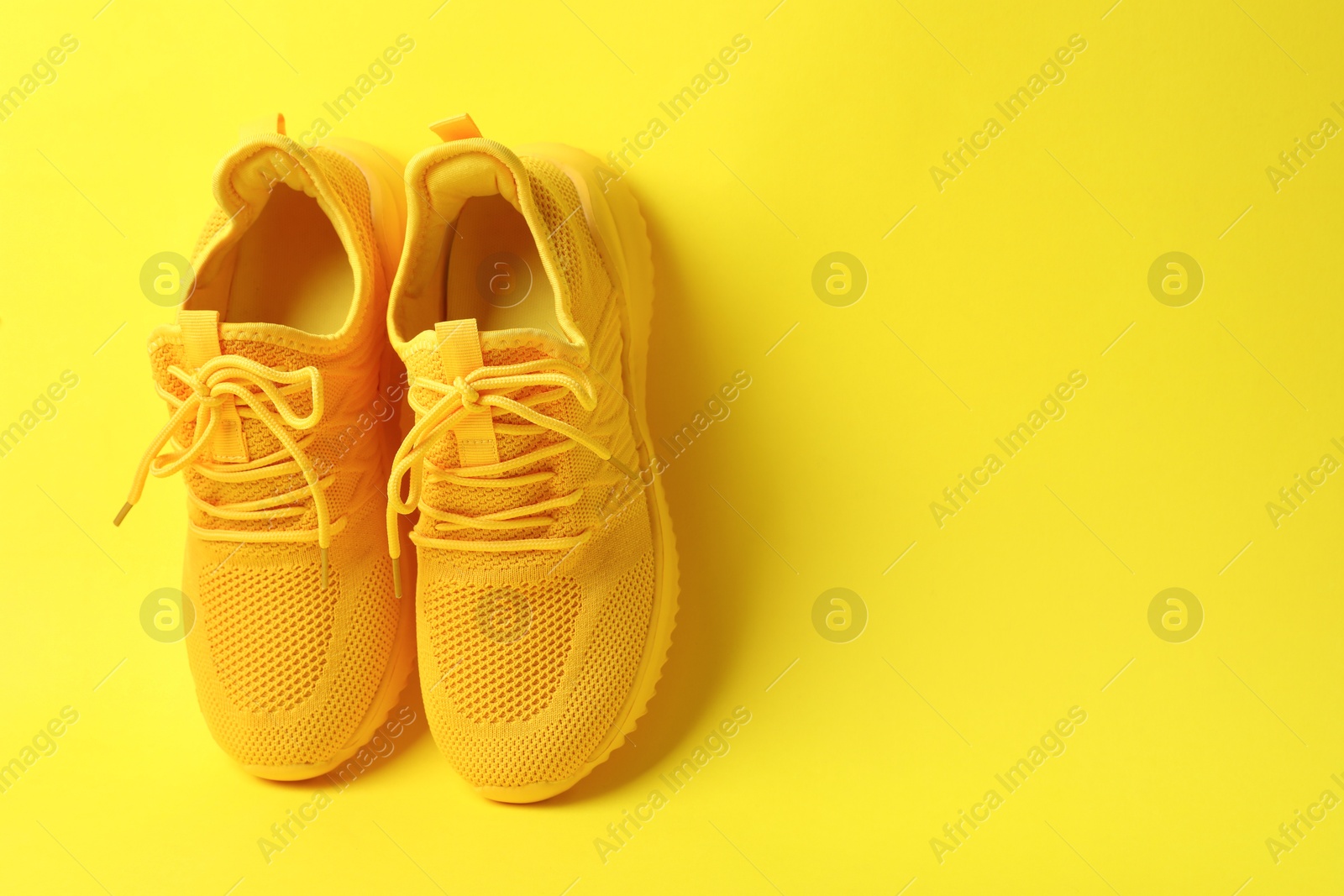 Photo of Pair of stylish sneakers on yellow background. Space for text