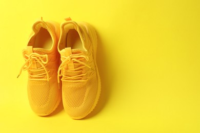 Photo of Pair of stylish sneakers on yellow background. Space for text