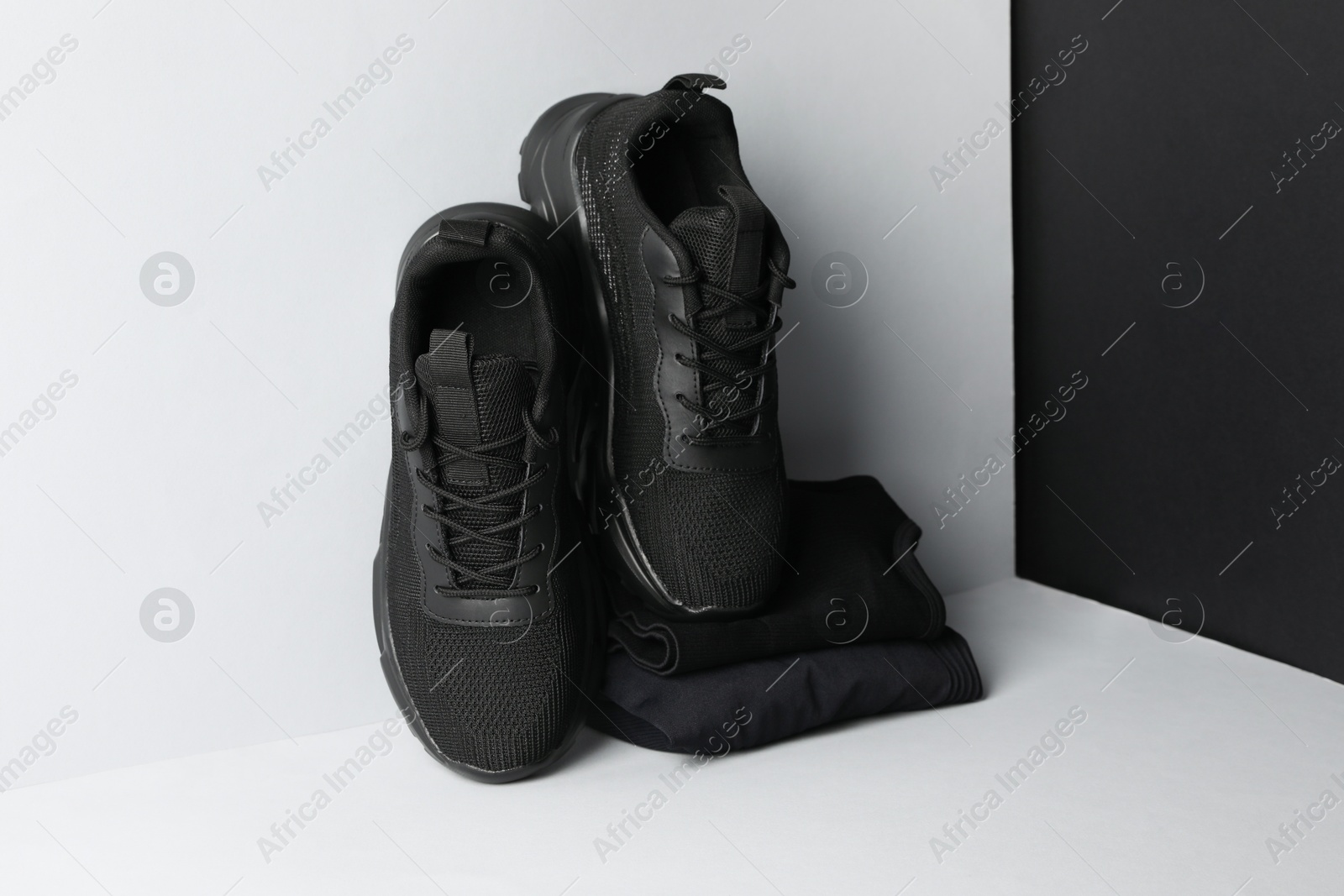 Photo of Pair of stylish sneakers and folded sportswear on color background