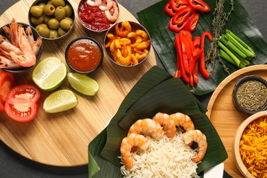 Photo of Cut banana leaves with different food, spices and sauce on dark table, flat lay. Healthy eco serving