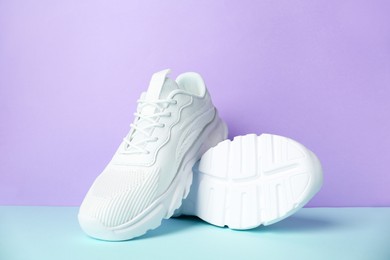 Photo of Pair of stylish white sneakers on color background