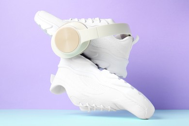 Photo of Pair of stylish white sneakers in air against color background