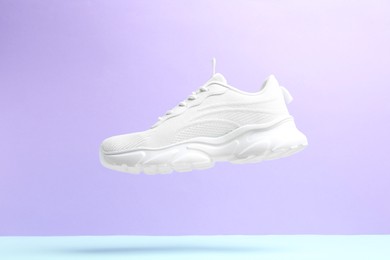 Photo of Stylish white sneaker in air against color background