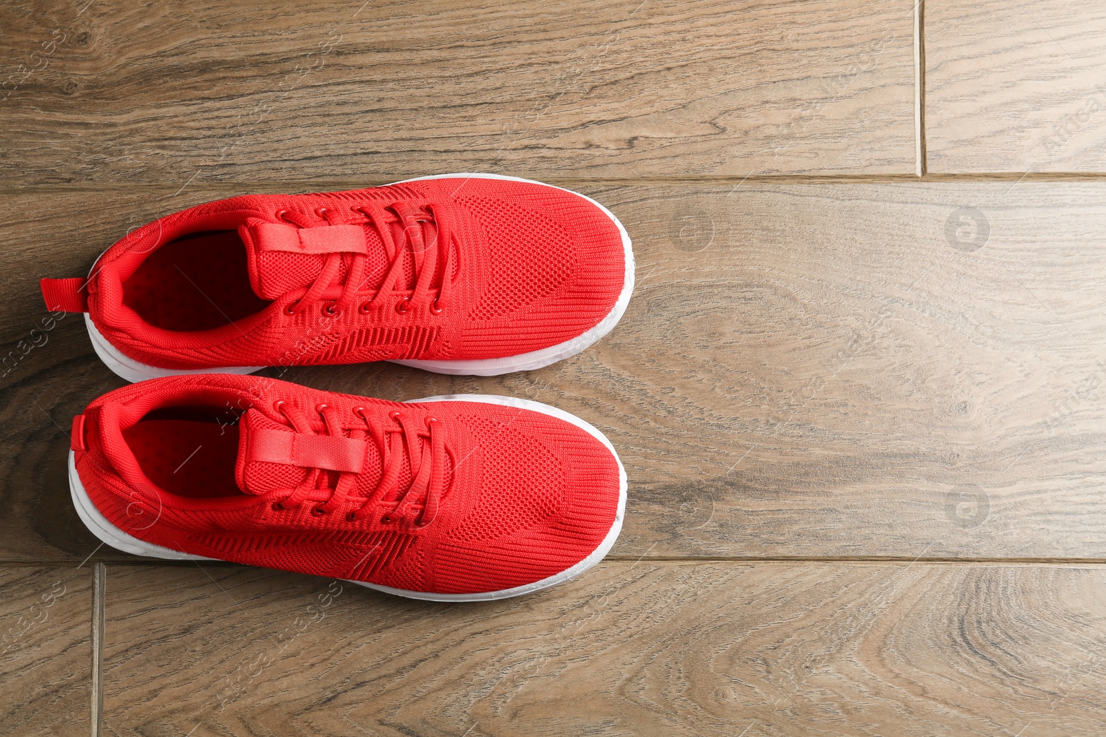 Photo of Pair of stylish red sneakers on wooden background, top view. Space for text